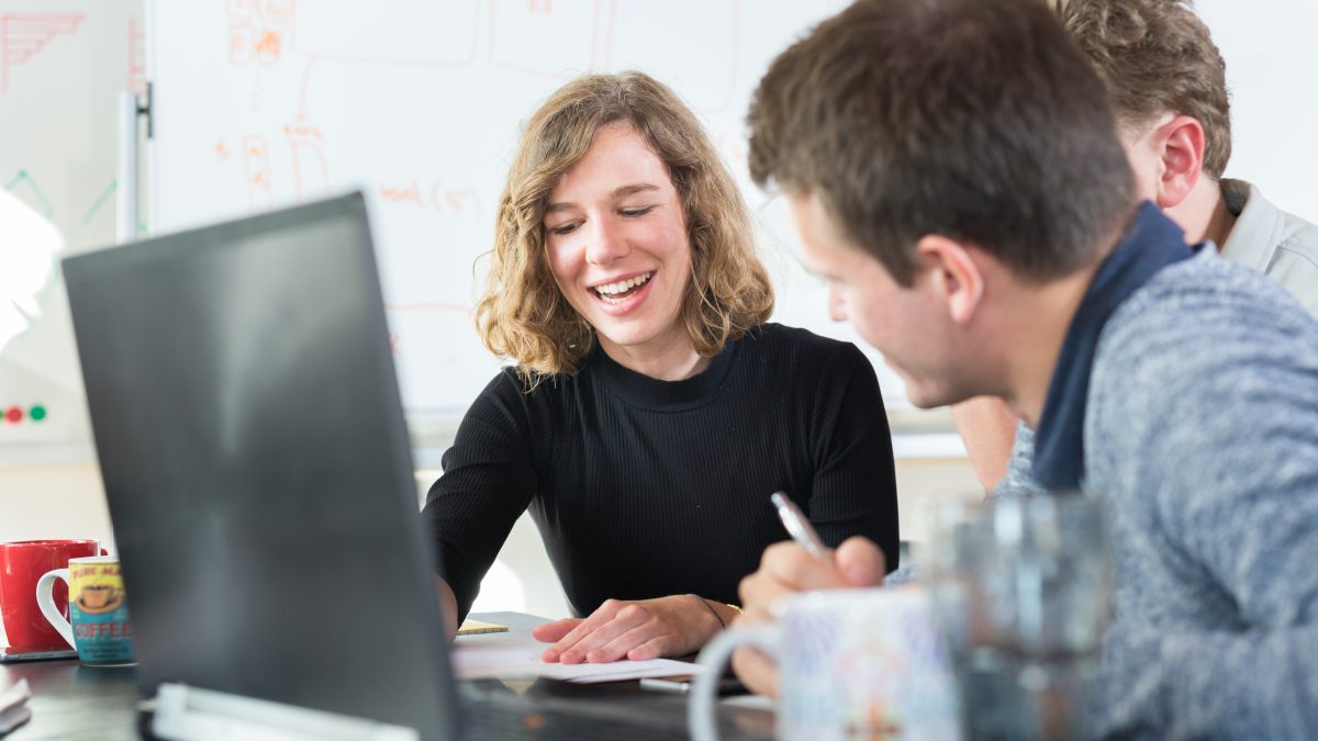 Smiling people working on a computer in an office.