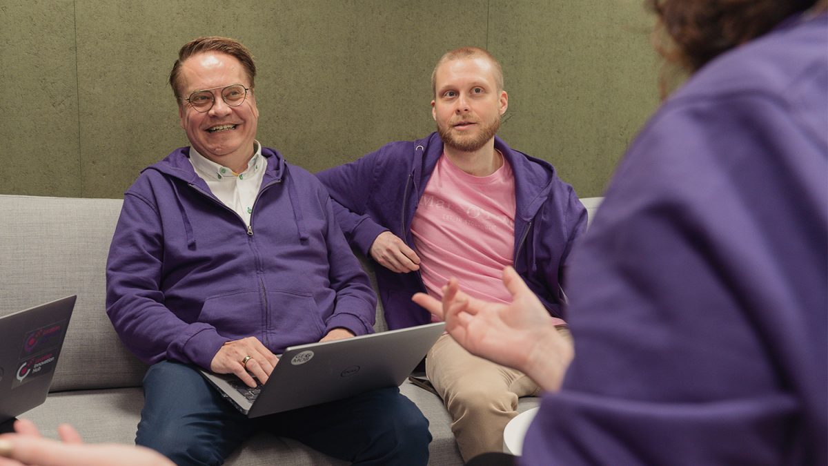 Antti Jakobsson & Joonas Jokela sitting on a couch and smiling.