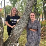 Niina Käyhkö and Sanna Jokela photographed next to a tree in a park-like landscape.