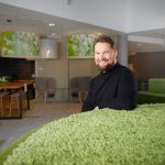 Sami Lankiniemi sits in a spacious office environment, leaning against a grass-green furniture.