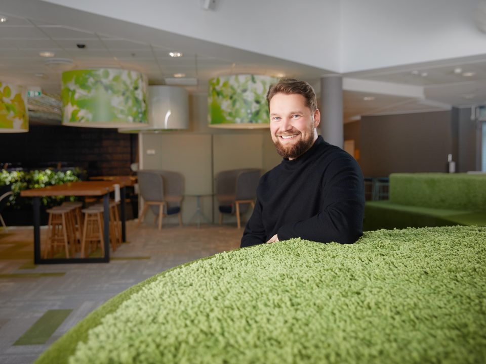 Sami Lankiniemi sits in a spacious office environment, leaning against a grass-green furniture.