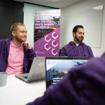 People from the LIH office chatting in a meeting room wearing purple hoodies.