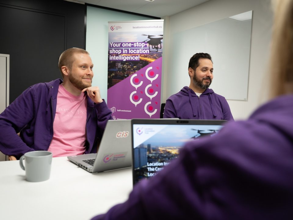 People from the LIH office chatting in a meeting room wearing purple hoodies.