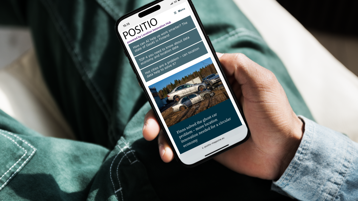 A person is holding a mobile phone with the front page of Positio Magazine on the screen.