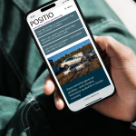 A person is holding a mobile phone with the front page of Positio Magazine on the screen.