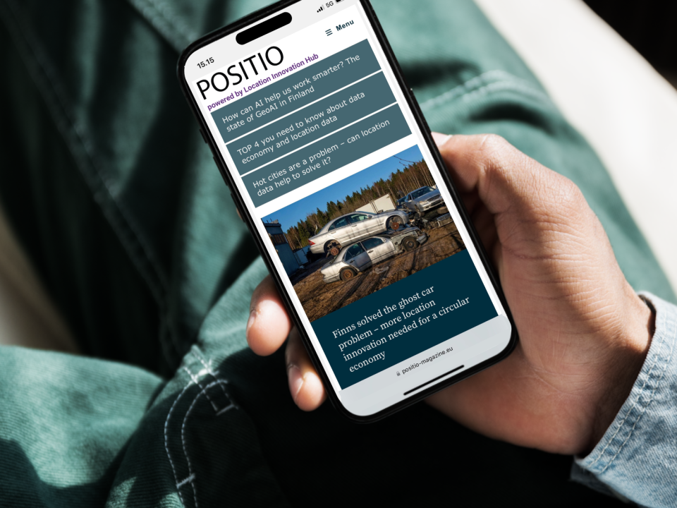 A person is holding a mobile phone with the front page of Positio Magazine on the screen.