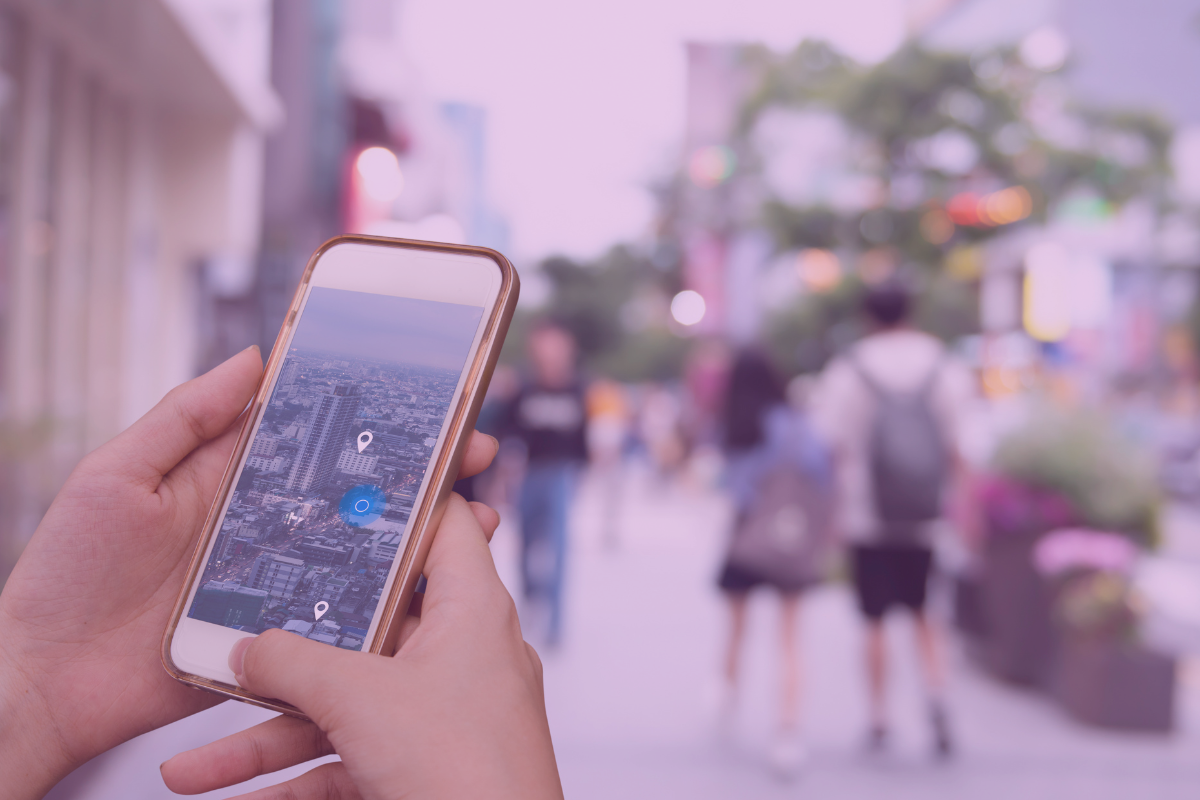 Hands holding a mobile phone showing a map visualisation in an urban street.