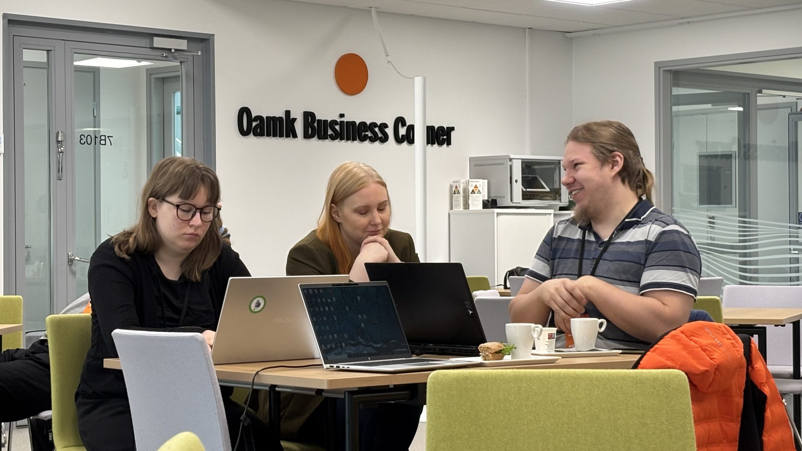 Hackathonin osallistujia työpöydän ääressä.