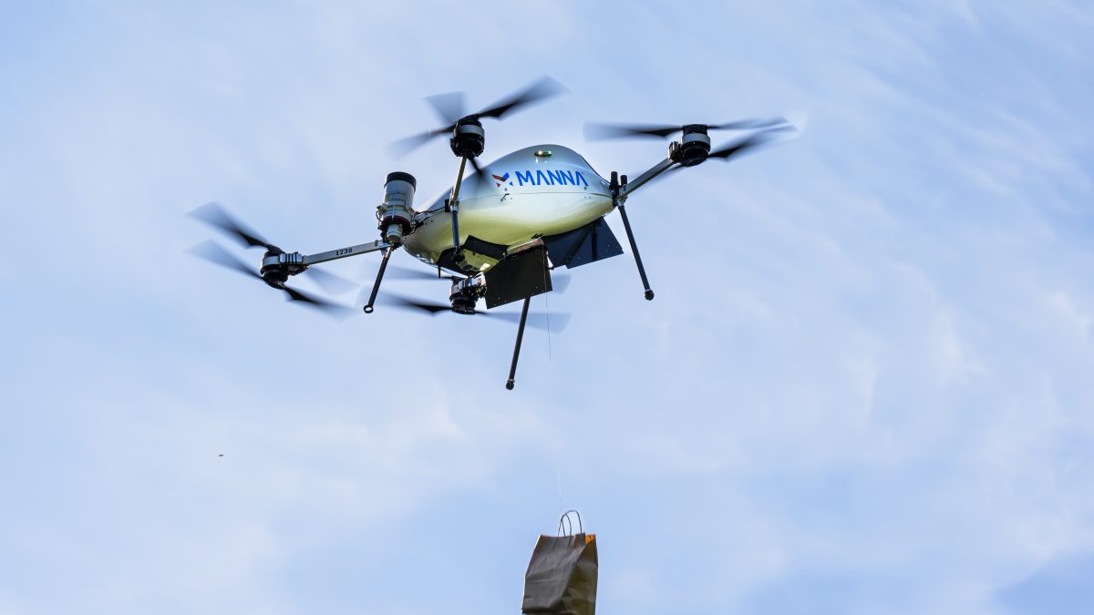 A drone flyinig in the air, delivering a food bag.