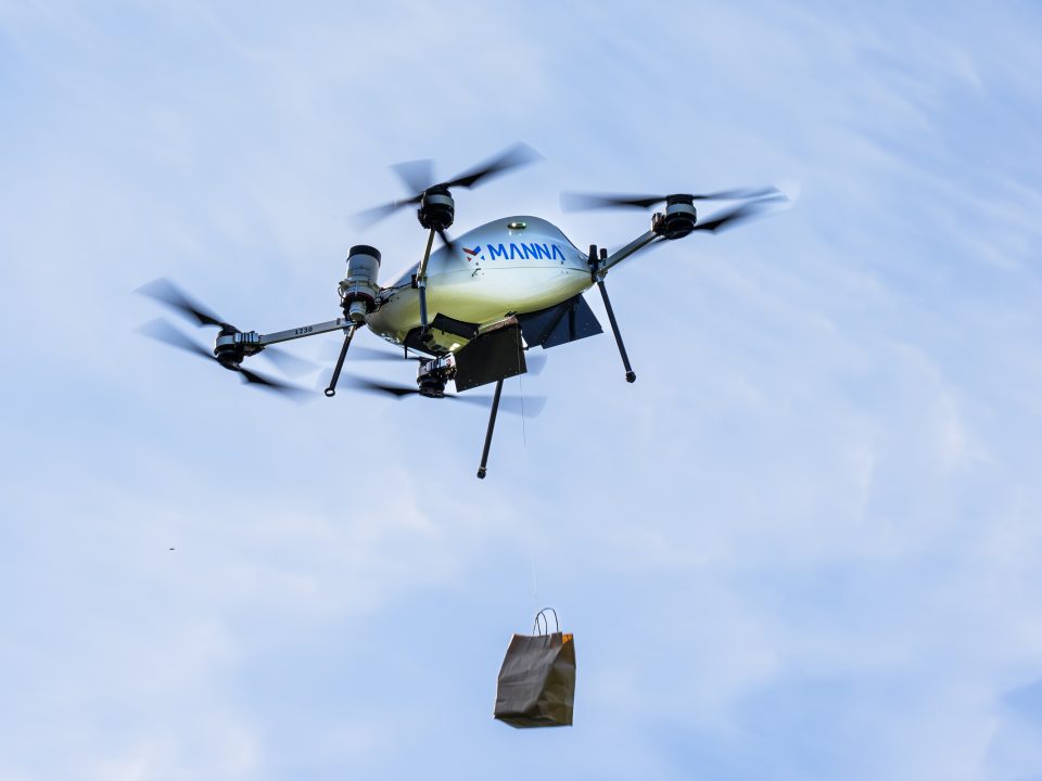 A drone flyinig in the air, delivering a food bag.