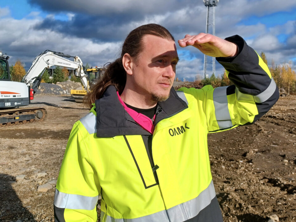 Jaakko Palmunen katselee rakennustyömaata OAMKin keltainen huomiotakki päällä.