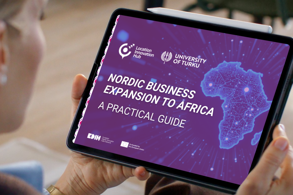A person holding a tablet displaying a digital guide titled “Nordic Business Expansion to Africa: A Practical Guide.” The screen has a purple background with a glowing map of Africa on the right and logos for Location Innovation Hub and University of Turku at the top. Additional smaller logos, including EDIH and the European Union emblem, appear at the bottom.