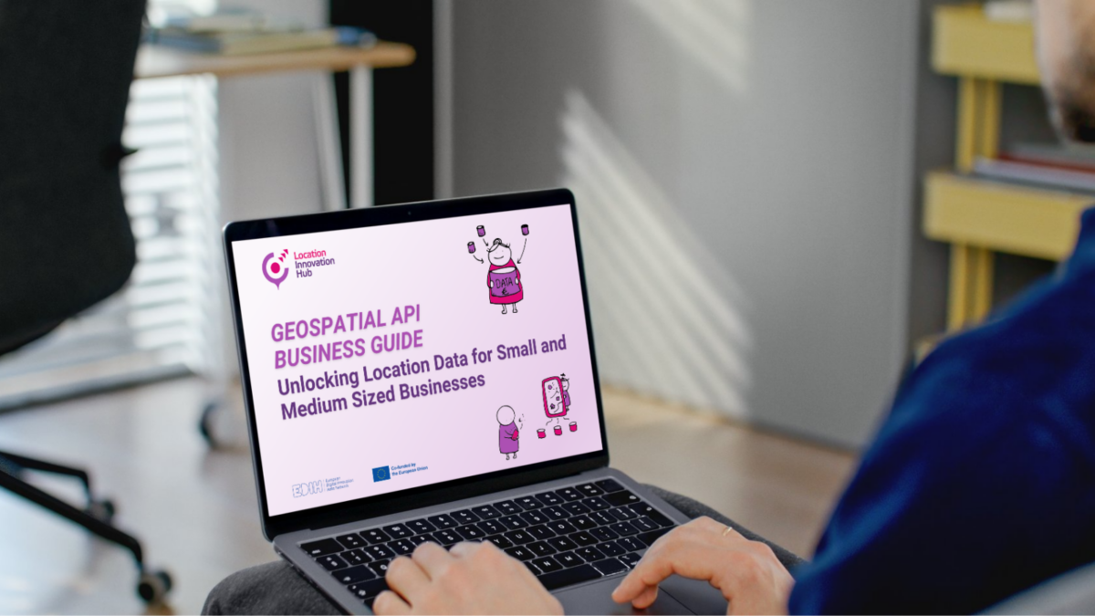 Henkilö työskentelee kannettavalla tietokoneella pöydän ääressä. Tietokoneen näytöllä näkyy esitys nimeltä “Geospatial API Business Guide: Unlocking Location Data for Small and Medium Sized Businesses”, jossa on violetteja kuvituksia.