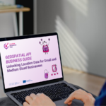 Henkilö työskentelee kannettavalla tietokoneella pöydän ääressä. Tietokoneen näytöllä näkyy esitys nimeltä “Geospatial API Business Guide: Unlocking Location Data for Small and Medium Sized Businesses”, jossa on violetteja kuvituksia.