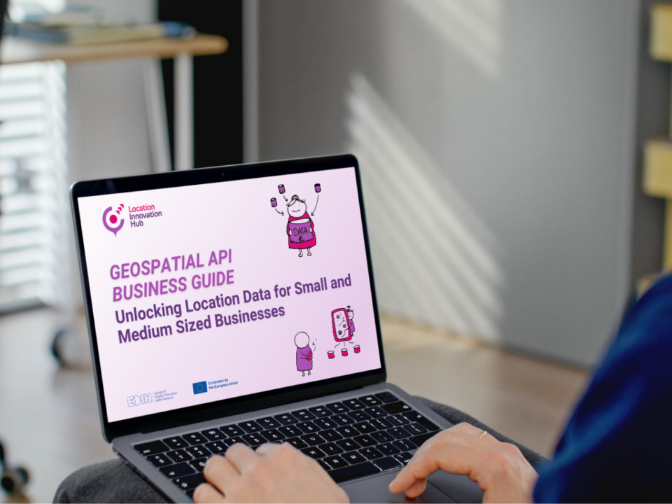 Henkilö työskentelee kannettavalla tietokoneella pöydän ääressä. Tietokoneen näytöllä näkyy esitys nimeltä “Geospatial API Business Guide: Unlocking Location Data for Small and Medium Sized Businesses”, jossa on violetteja kuvituksia.