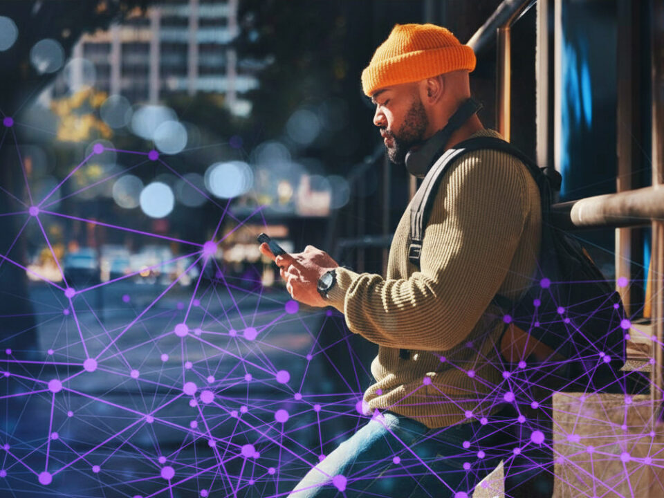 Person standing in an urban street setting, looking at a smartphone, with an abstract digital network overlay representing data connectivity.