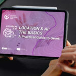 Person holding a tablet displaying the GeoAI guide “Location & AI: The Basics”.