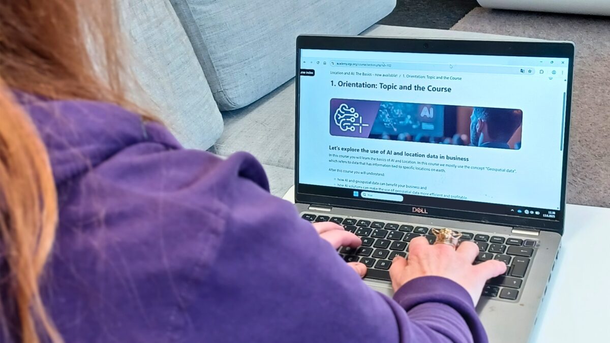 A person working on a laptop displaying an online course about the use of AI and location data in business.