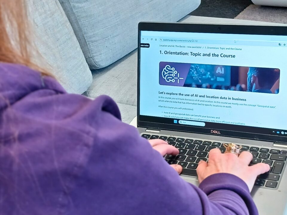 A person working on a laptop displaying an online course about the use of AI and location data in business.